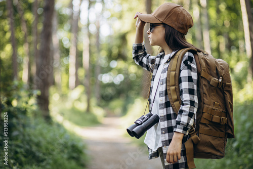 Girl traveler with rucksuck and camera through the shoulder walking in the forest photo