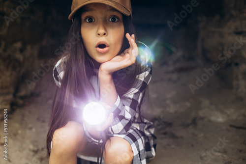 Girl with flashlight in cave searching antiquity photo