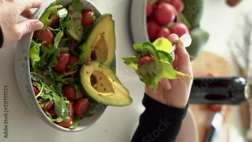 Happy beautiful young woman eating healthy food at home. Salad with Avocado and vegetables in bowl. Healthy food concept. 4k footage. 4k footage. no face. Vertical shoot.
