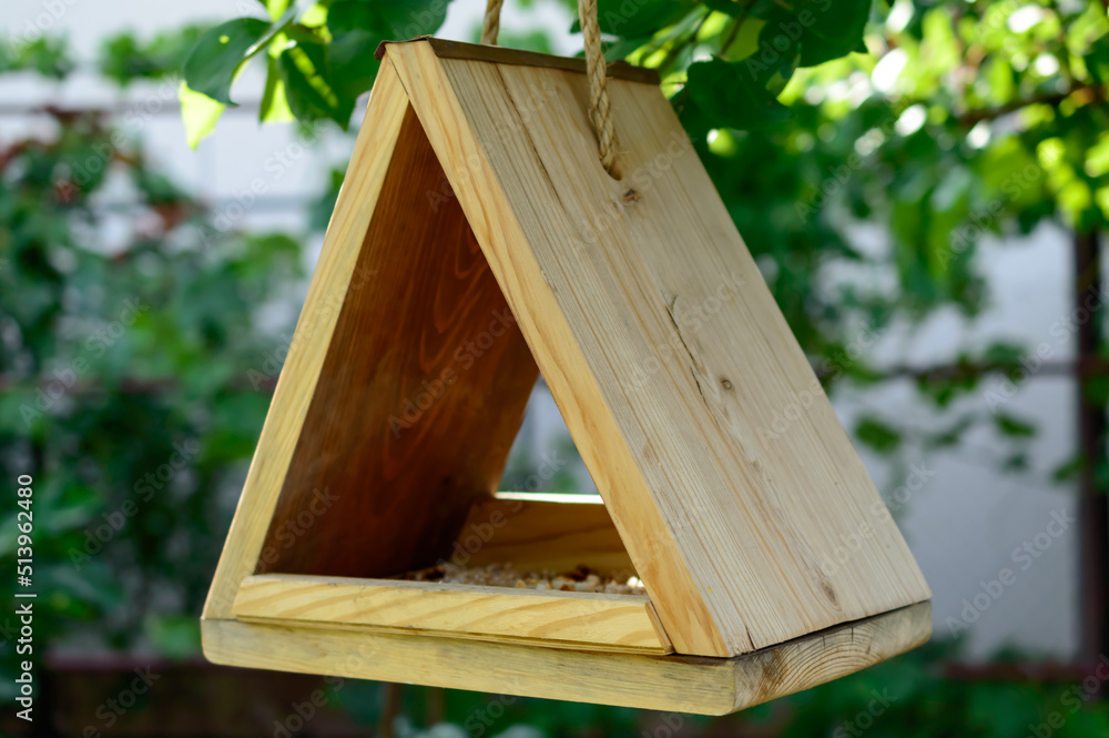 Small wooden birdhouse is hanging on a natural rope on the tree. Waiting for the birds. DIY birdhouse. Background picture. Small wooden birdhouse is hanging on a natural rope on the tree. Waiting for the birds. DIY birdhouse. Background picture.