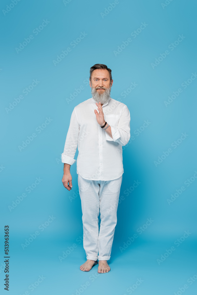 full length of master guru in white clothes showing blessing gesture on blue. full length of master guru in white clothes showing blessing gesture on blue.