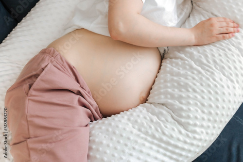 Beautiful pregnant woman relaxing or sleeping with belly support pillow in bed