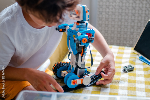Kid collects robot from plastics details and programmed on tablet, robotics.