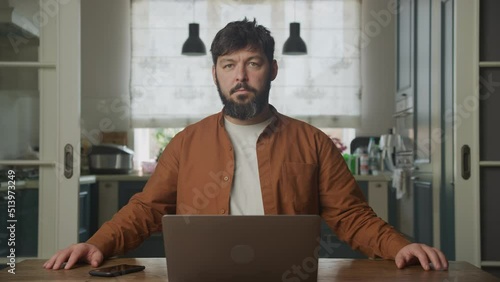 Man looking at camera and waiting in front his laptop