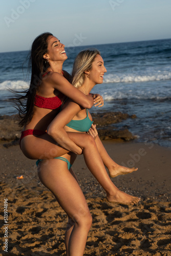 two girls in bikini spending a day on the beach at sunset
