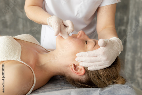 Female physiotherapist, chiropractor, osteopath doing anti wrinkle manual myofascial face massage by fingers in mouth