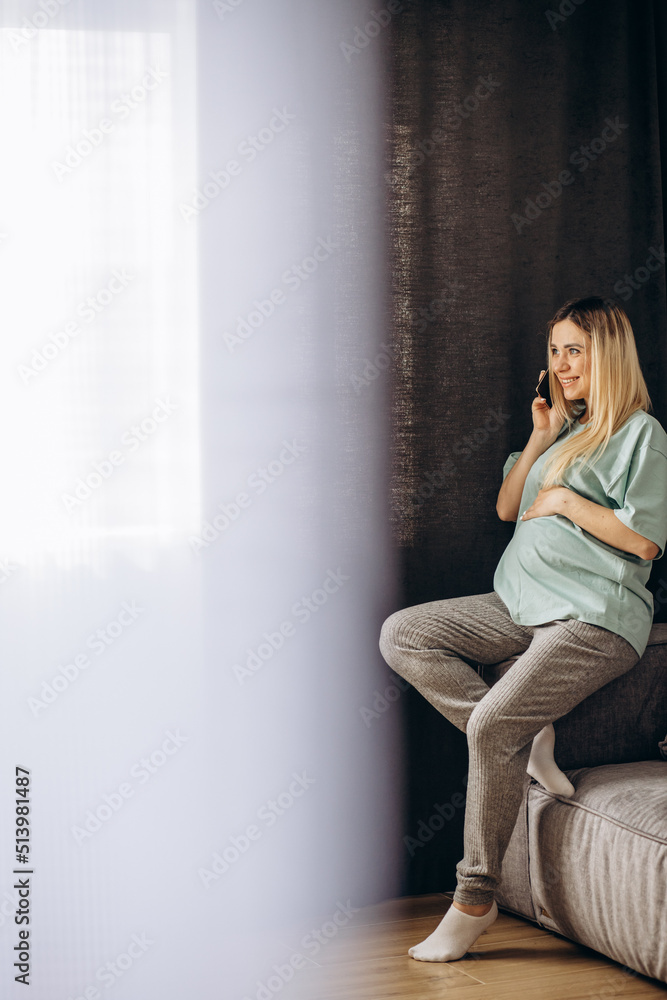 Pregnant woman talking on the phone at home Pregnant woman talking on the phone at home