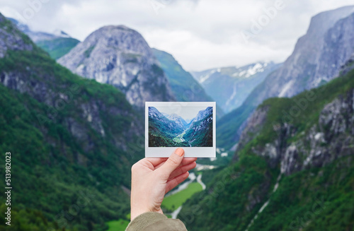 Hand holding up polaroid instant photo of travel destination glacial valley wanderlust inpiration concept photo