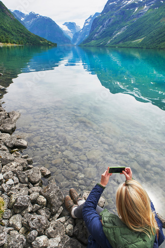 Adventure woman taking photo of beautiful nature mountail lake with smart phone travel explore discover photo