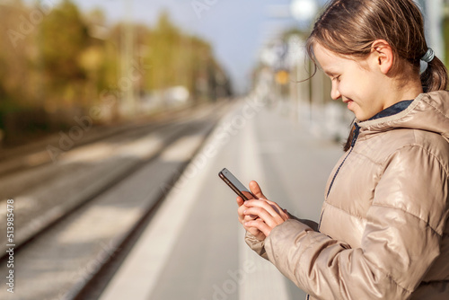 Mobile phone App help Travel. Happy Girl used Smart phone on Railway Station. Mobile App in Phone for Travel.