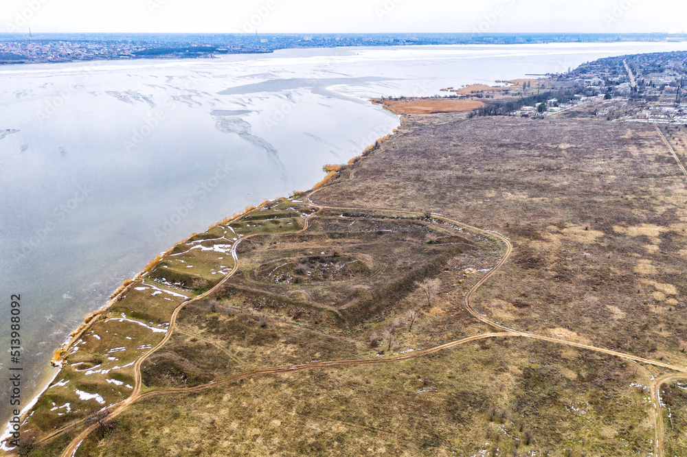 Historical fortification in the field. The remains of the defense system of the city of Nikolaev. Flight over the winter river