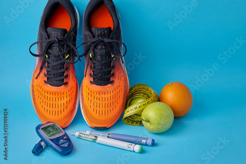 Orange sneakers, fruits, measuring tape, glucometer and insulin syringe pens on a blue background