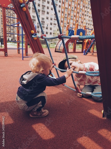 Brothers playing together on the playground. Friendship between older and younger siblings. Two children having fun.