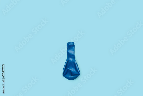 Globo de color azul desinflado de cumpleaños sobre un fondo celeste liso y aislado. Vista superior y de cerca. Copy space