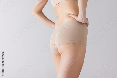 Cropped image of female body, buttocks in beige underwear isolated over grey studio background. Anti-cellulite care.