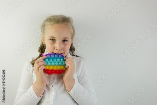 Baby girl playing with trendy rainbow pop it fidget. Childhood, anti-stress therapy, autism concept