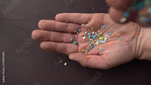 Close-up on micro plastic particles falling in a person hand. The concept for water pollution and global warming. Macro shot on a bunch of microplastics that cannot be recycled