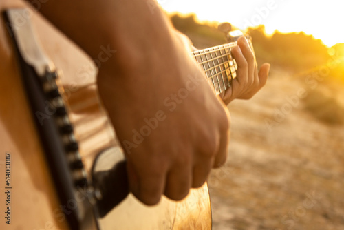 Guitar and sunset. Playing acoustic guitar during sunset. Playing music during sunset. Enjoying the sunset with friends and playing acoustic guitar music during the golden hour. Guitar backgrounds © anasphotos2000