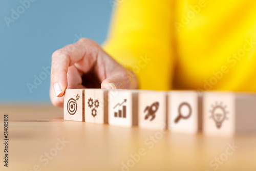 Businesswoman hand arranging wooden cube block with icon business strategy