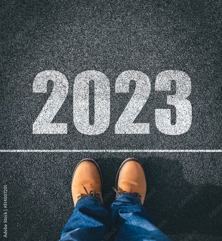 New year 2023, concept. 2023 inscription on the asphalt. The man in boots takes a step into the new year 2023.