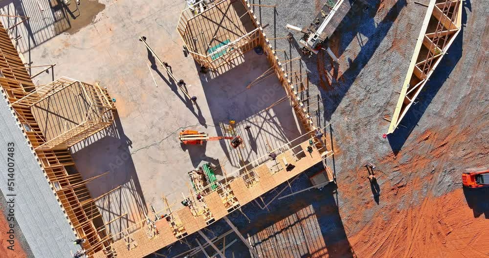 A carpenter installs engineered wood trusses on a new home an aerial top view A carpenter installs engineered wood trusses on a new home an aerial top view