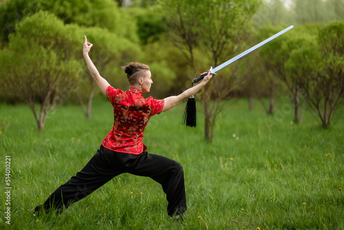 Asian woman with sword training with tai chi in the park, chinese martial arts, healthy lifestyle concept.