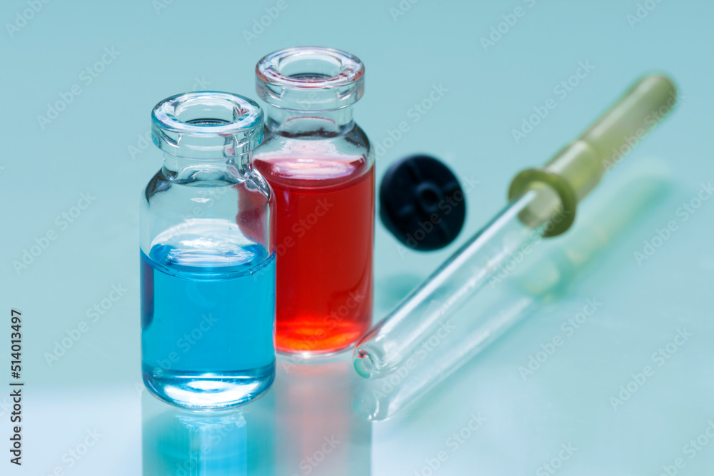 Two medical bottles with potions and pipette on glass table. Two medical bottles with potions and pipette on glass table.