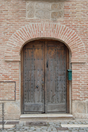 brick facade with round arch and old wooden door © claverinza