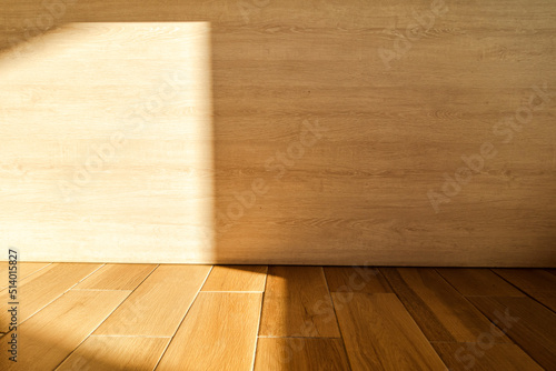 The sun shines on the corners of the wood wall and floor