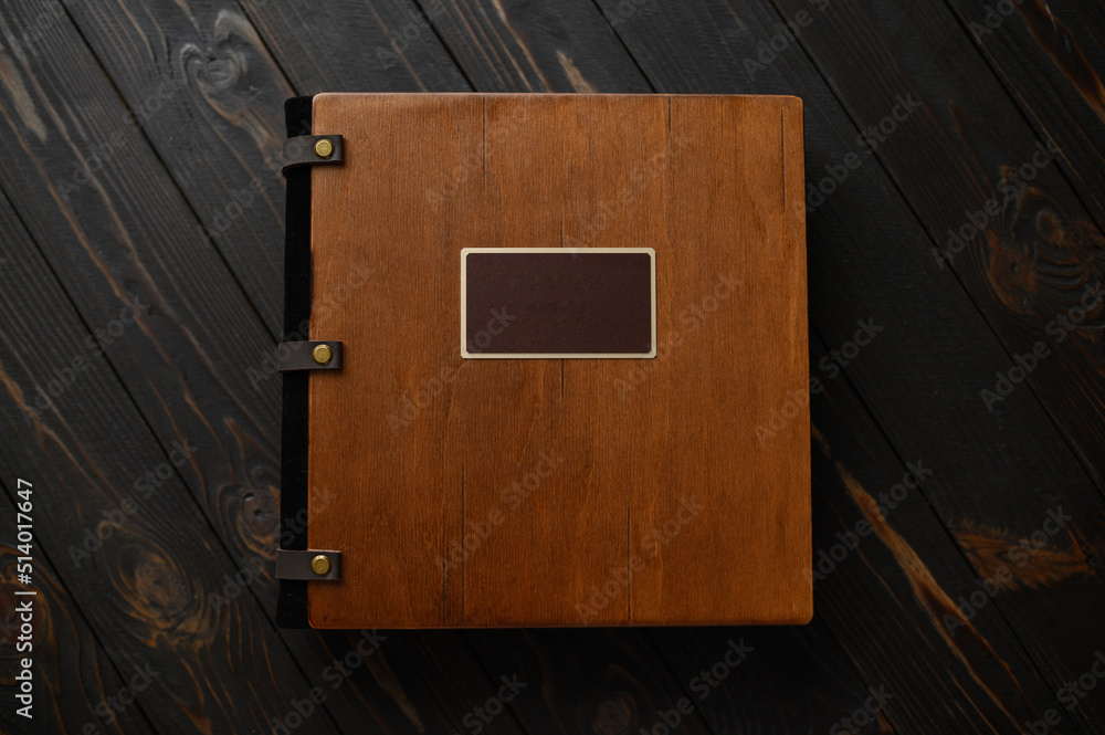 An old photo album with a wooden cover and a shield on a rustic table. free logo - obrazy, fototapety, plakaty 