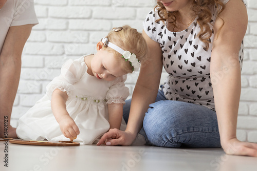 Child girl with cochlear implant plays at home with mother and father. Hear impairment and diversity and hearing aid