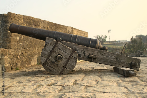 Side view of a movable sixteenth century Portuguese cannon made of metal and a wooden base. It's located on a bastion of Diu Fort, Diu, India photo