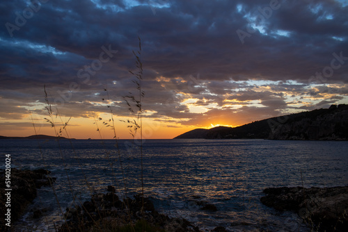 Sunset behind the mountains after storm on sea