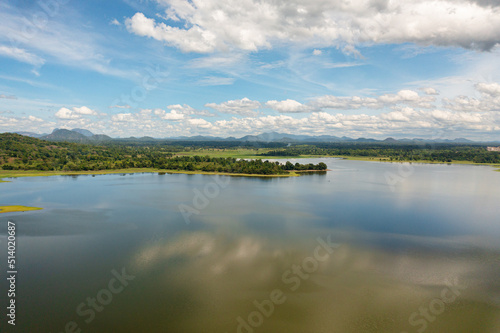 Aerial drone of valley with a lake and tropical vegetation against a blue sky and clouds. Sorabora lake  Sri Lanka.