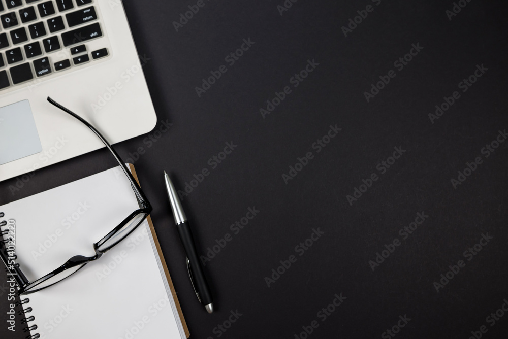 Top view photo of laptop with notepad, pen and glasses on isolated black background. Top view photo of laptop with notepad, pen and glasses on isolated black background.