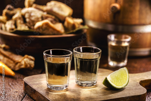 Cachaça, pinga, cana or caninha is the sugar cane brandy, a typical drink from Brazil, with a crackling appetizer in the background