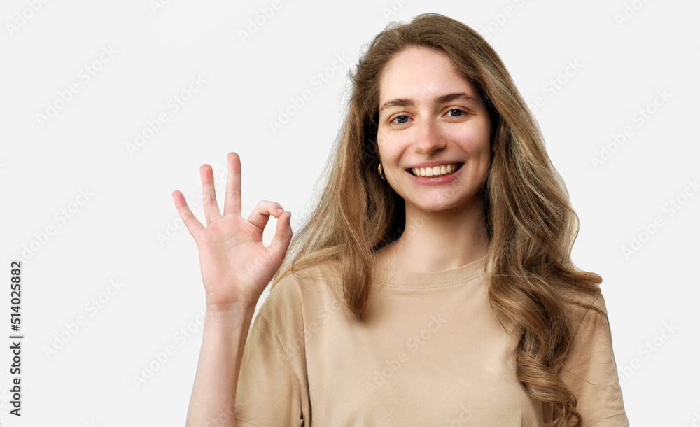 Laughing beautiful girl shows ok gesture. Pretty woman smiling. Studio portrait isolated on white background Laughing beautiful girl shows ok gesture. Pretty woman smiling. Studio portrait isolated on white background