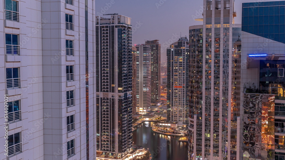 Fototapeta premium Tall residential buildings at JLT aerial day to night timelapse, part of the Dubai multi commodities centre mixed-use district.