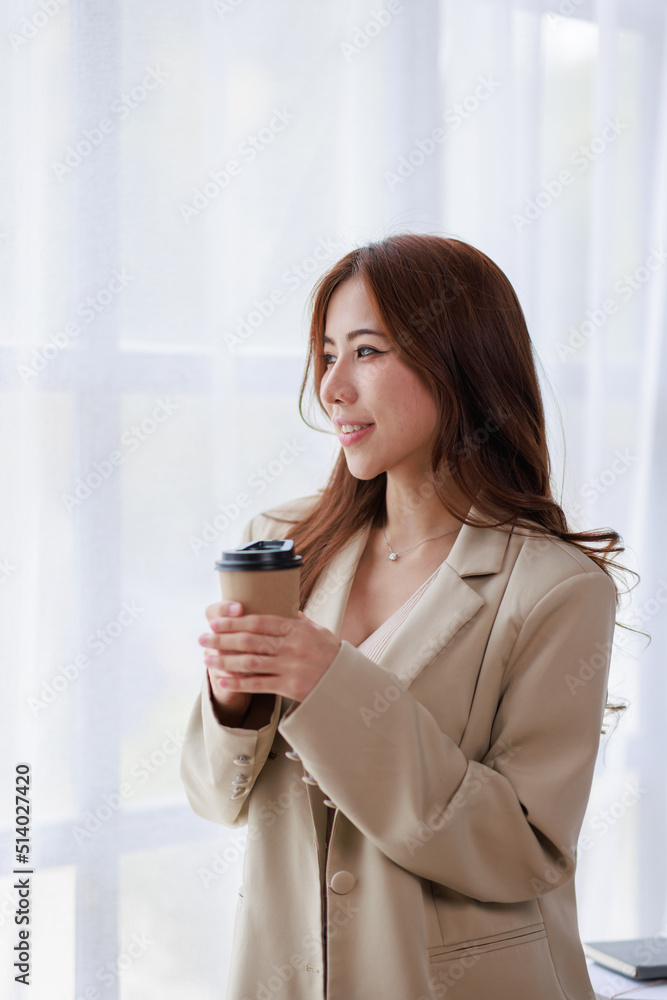 Business Asian woman holding a cup of coffee at workplace Business Asian woman holding a cup of coffee at workplace