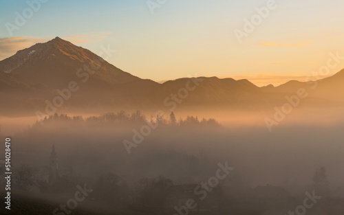 Misty sunrise over the farmlands of Slovenia. Sunlight is penetrating the trees and bushes. © gljivec