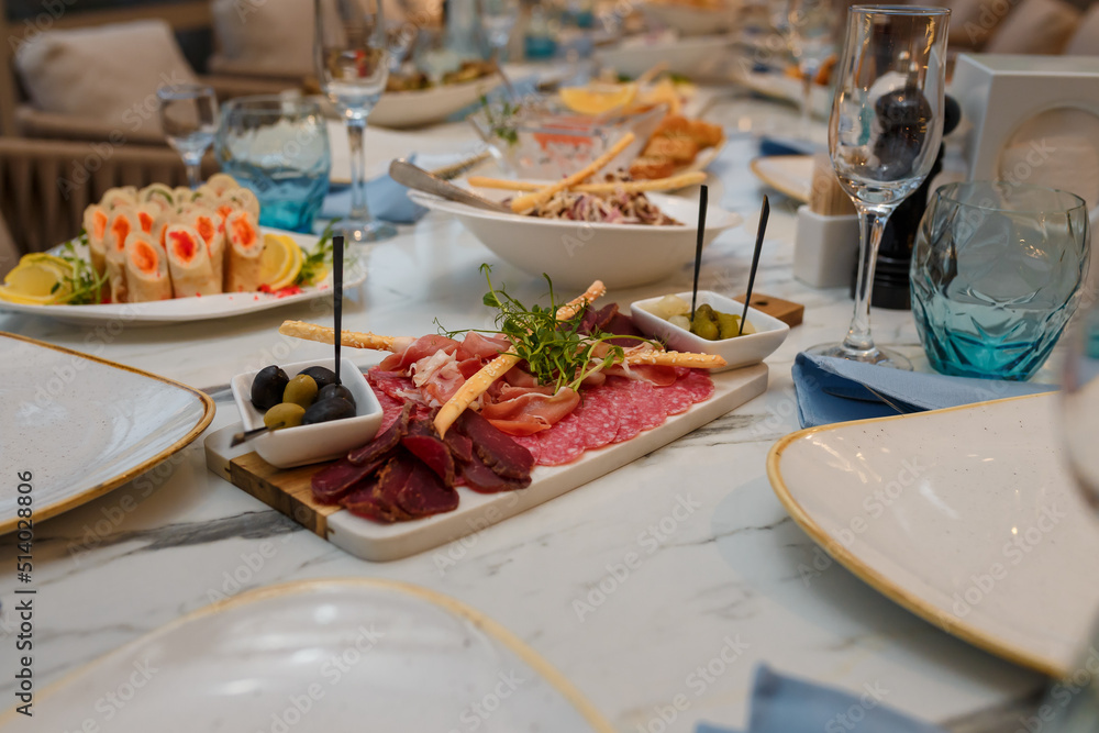 Festive table with caviar appetizers, ham, sausage and meat plates with microgreen. Empty glasses, plates for guests