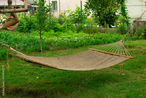 Hammock stands in the green garden of the cottage. The concept of vacation in the summer or in warm countries.