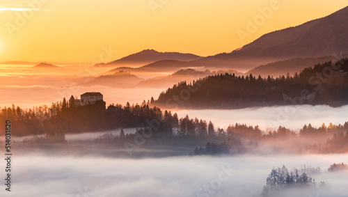 Church and villages hiding in the early morning fog. A misty sunrise in the countryside. © gljivec