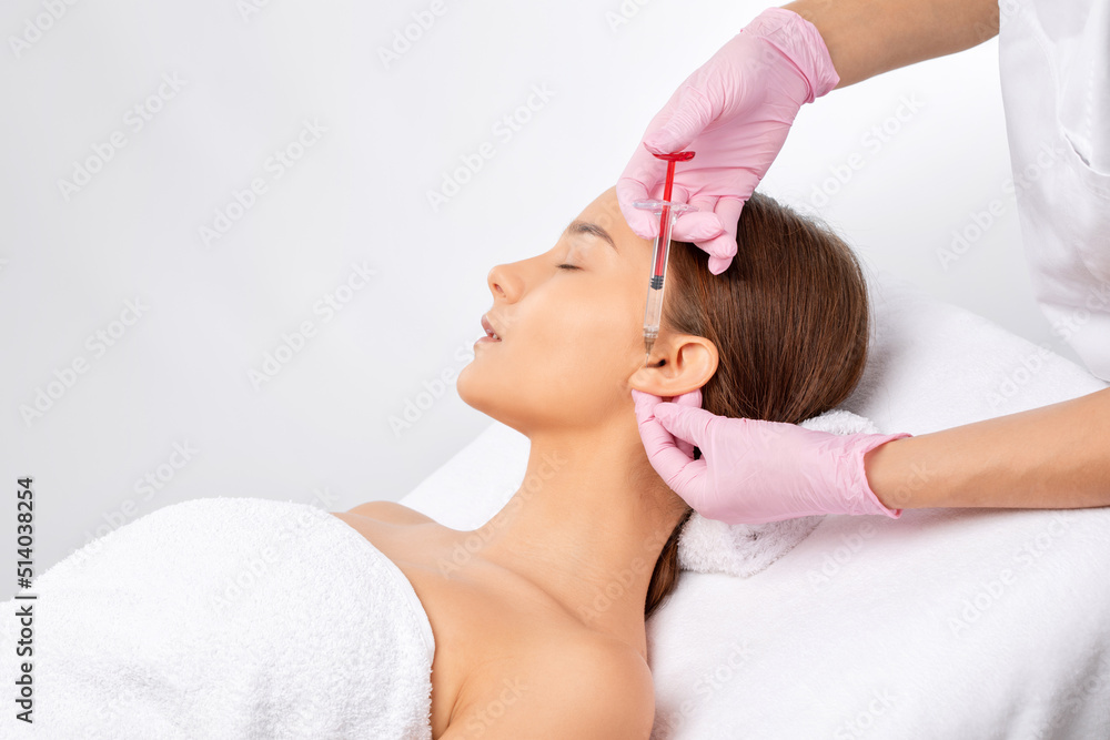 Naklejka premium Cosmetologist makes rejuvenating anti wrinkle injections on the face of a beautiful woman. Female aesthetic cosmetology in a beauty salon.