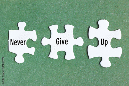 Motivational text on three pieces of white jigsaw puzzle on green background.