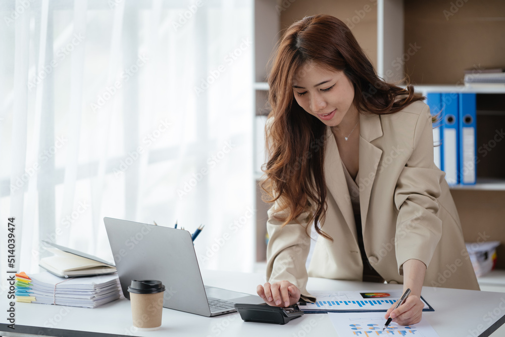 Happy smiling business woman using laptop and calculator for working at home or office space. Happy smiling business woman using laptop and calculator for working at home or office space.