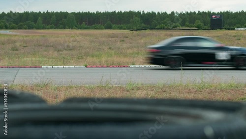 Two race cars as competitors on a race track. The fast driving sports cars are competing and passing by with a high speed. Motorsport outdoor on the asphalt. Viewing from the side.