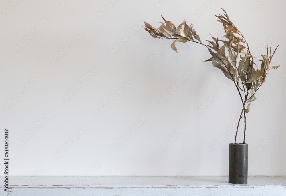 Vase with flowers on the table. Branches in the interior. Dried flowers on a light background.