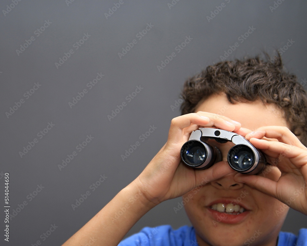 boy looking through binoculars on grey background stock photo boy looking through binoculars on grey background stock photo
