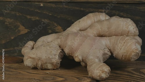 Close-up of ginger root on a dark wooden table and brown background. Dolly shot. Ginger is used to treat colds and viral diseases. photo